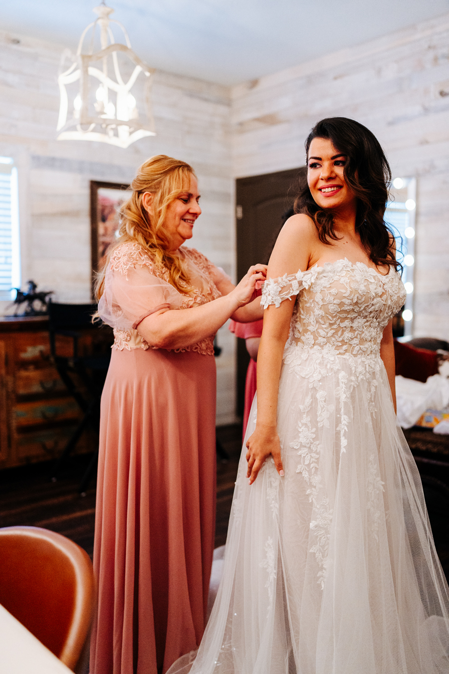 Mother helping the bride put on her dress